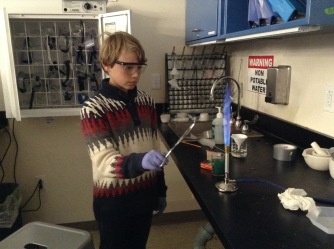 A student doing a flame test to see if the metal was copper (it should burn green if it was)